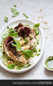 roasted radicchio salad with feta, green tahini, Pine nuts and basil pesto. Radicchio rosso di treviso tardivo, italian red chicory. Healthy Meal recipe preparation. Plant-based dishes. Green living.