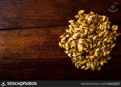 Roasted salty pumpkin seeds on wooden table