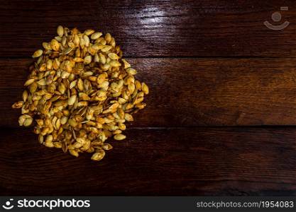 Roasted salty pumpkin seeds on wooden table