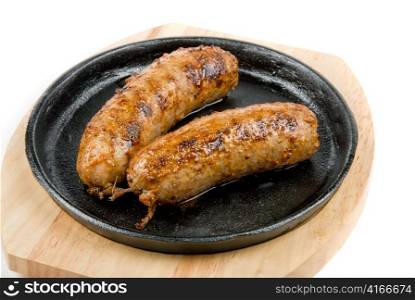 Roasted sausages close-up at pan on a white background