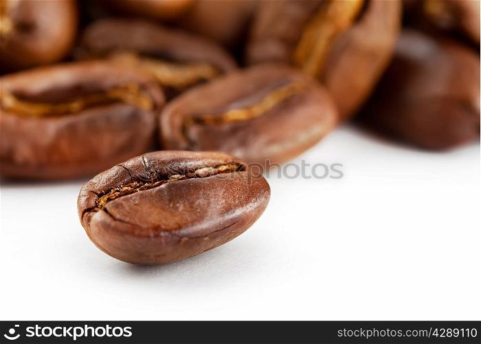 Roasted shiny grains of coffee isolated on white background