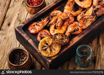 Roasted shrimps and lemon on cutting board. Delicious roasted shrimps