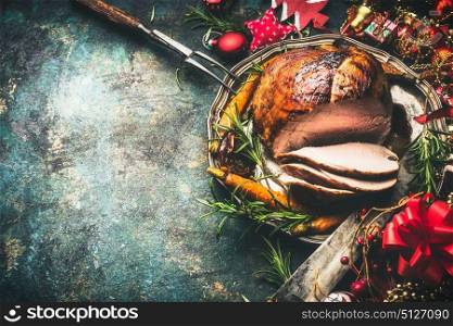 Roasted sliced Christmas ham on festive table background with decoration, top view