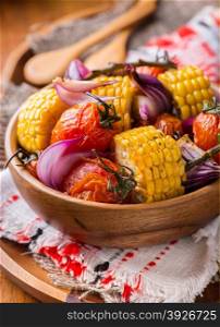 Roasted vegetables in wooden bowl. Tomato, corn and onion. Closeup, selective focus