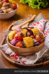 Roasted vegetables in wooden bowl. Tomato, corn and onion, selective focus