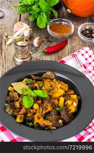 Roasted vegetables with pumpkin and mushrooms on a black plate. Studio Photo. Roasted vegetables with pumpkin and mushrooms on a black plate