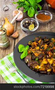 Roasted vegetables with pumpkin and mushrooms on a black plate. Studio Photo. Roasted vegetables with pumpkin and mushrooms on a black plate