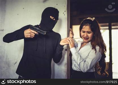 Robber force woman to steal her golden necklace by hand gun in corner of building. Fear of women during facing to thieves. Criminal sexual and illegal violence crisis concept