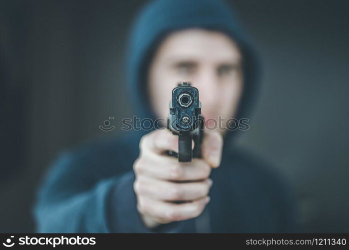 Robber or criminal is aiming with a black gun, blurry face