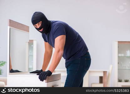 Robber wearing balaclava stealing valuable things