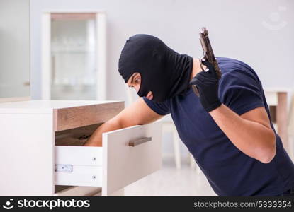 Robber wearing balaclava stealing valuable things