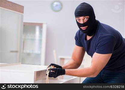 Robber wearing balaclava stealing valuable things