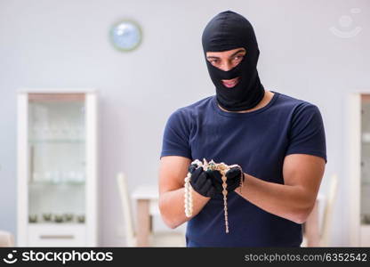 Robber wearing balaclava stealing valuable things