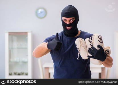 Robber wearing balaclava stealing valuable things