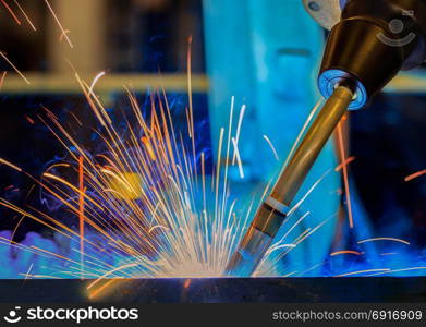 Robot is welding metal part in car factory