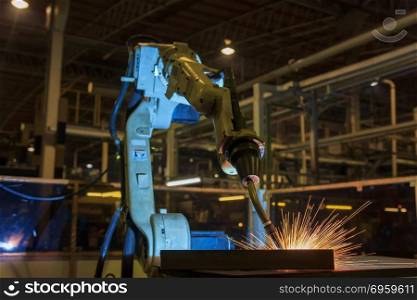 Robot is welding metal part in factory