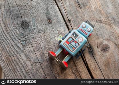Robot toy, symbol for a chatbot or social bot and algorithms. Wood texture.