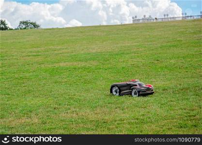 Robotic lawn mower on grass, side view. Garden modern remote technology. Close-Up Of Lawn Mower On Field.. Robotic lawn mower on grass, side view. Garden modern remote technology.