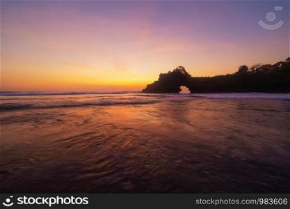 Rock cliff near Pura Tanah Lot, in Bali at sunset. It is one of the most popular of tourist attraction. Indonesia. Nature landscape background of travel trip and holidays vacation in Indonesia.