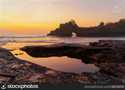 Rock cliff near Pura Tanah Lot, in Bali at sunset. It is one of the most popular of tourist attraction. Indonesia. Nature landscape background of travel trip and holidays vacation in Indonesia.