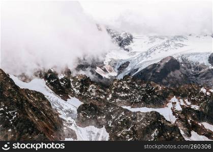Rock cliff rise high behind cloud and deep snow mountain valley of Titlis in Engelberg, Switzerland