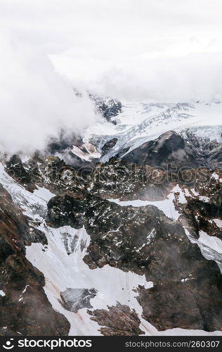 Rock cliff rise high behind cloud and deep snow mountain valley of Titlis in Engelberg, Switzerland