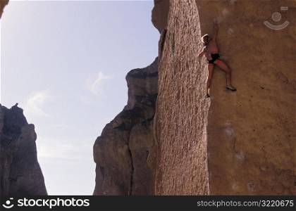 Rock Climber Clinging To Side Of Cliff