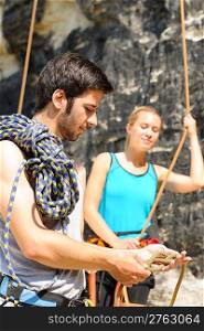Rock climbing active young man showing mountaineer woman rope knot