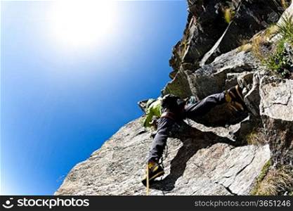 Rock climbing: climber on a steep wall. Clear sky, day light. West italian Alps, Europe.