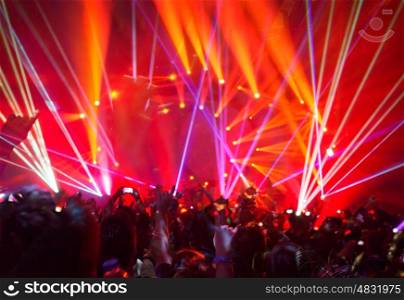 Rock concert background, large group of people enjoying party, having fun in night club in bright red laser light, active night life, music star performance