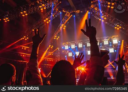Rock concert, people with raised up hands dancing and enjoying loud music, having fun in night club, with pleasure spending time on musicl festival