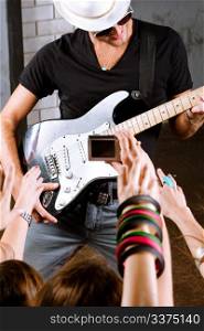 Rock guitarist playing in front of a cheering crowd.