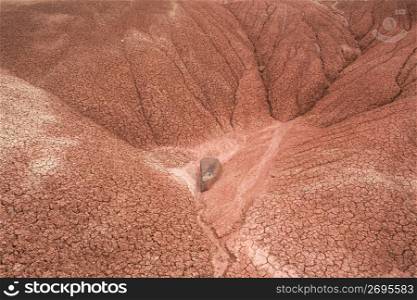 Rock in valley formed of dry, cracked dirt mounds in desert area