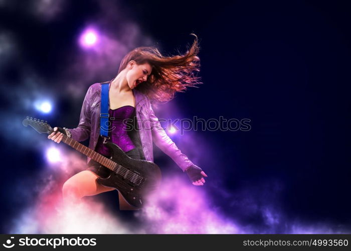 Rock passionate girl with black wings. Young attractive rock girl playing the electric guitar