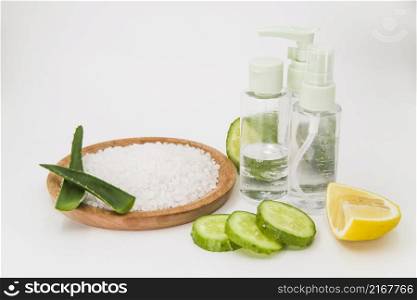 rock salt wooden plate cucumber slices lemon spray bottle white backdrop