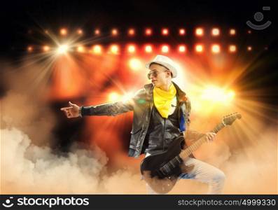Rock star. Young man, rock musician in jacket playing guitar