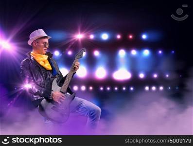 Rock star. Young man, rock musician in jacket playing guitar