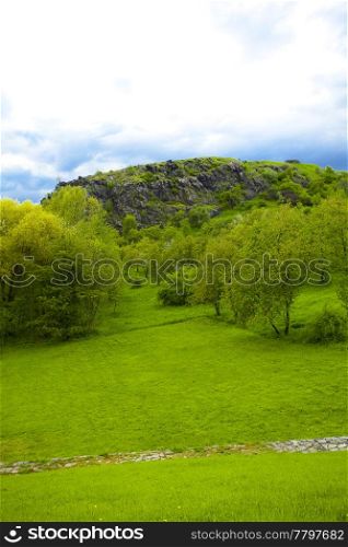 rock with green against the blue sky with clouds