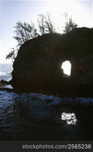 Rock with hole in it in Pacific ocean off island of Maui, Hawaii.