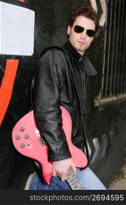 rocker rock star man on black graffiti holding red electric guitar leather jacket