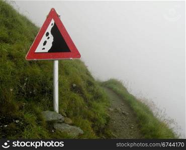 rockfall sign in the alps. rockfall sign on a hiking path on a steep slope in the alps