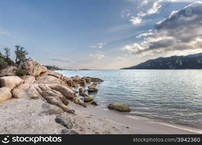 Rocks and boulders in a translucent turquoise sea and blue skies at Santa Giulia beach in Corsica