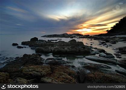 rocks in calm sea with beautiful sunrise background