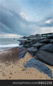 Rocks in the foreground, on the beach, next to Southwold Pier, in Suffolk, at sunrise
