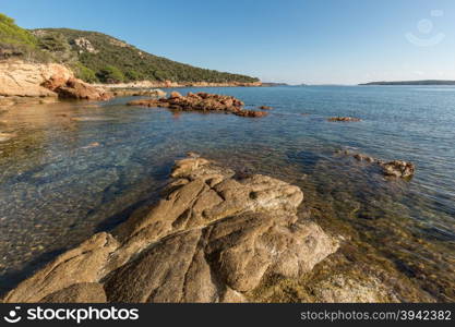 Rocks jutting out into a calm, crystal clear, mediterranean sea at Palombaggia beach in Corsica