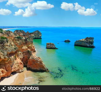 Rocks near beach Dos Tres Irmaos. Top view with blue sky (Portimao, Alvor, Algarve, Portugal). People in boat are unrecognizable.