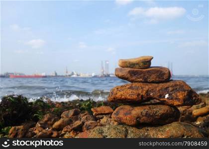 Rocks on the coast of the sea with shipyard as background. Rocks on the coast of the sea