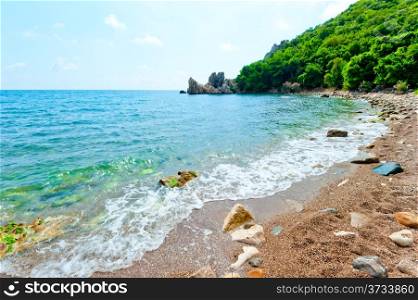 Rocky beach, green hill, azure waters of the sea.
