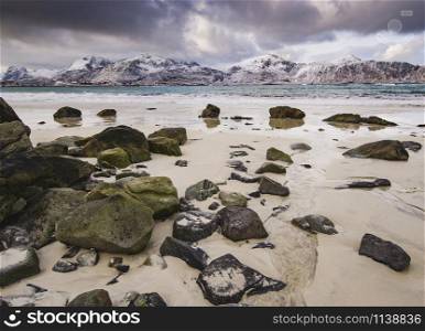 Rocky coast of fjord of Norwegian sea in winter with snow. Haukland beach, Lofoten islands, Norway