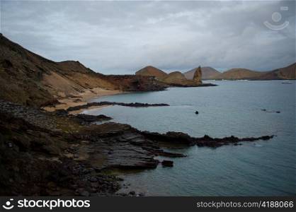 Rocky coast with Pinnacle Rock in the background, Bartolome island, Galapagos Islands, Ecuador